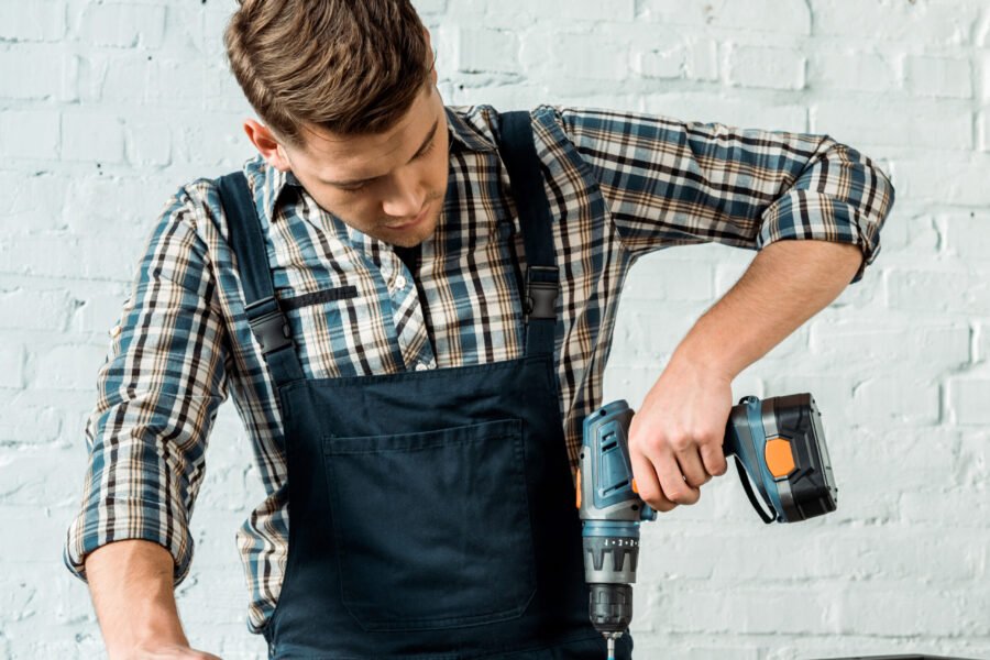 focused installer holding hammer drill near rack
