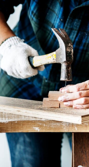 Woman carpenter using hammer pushing nail on a wood