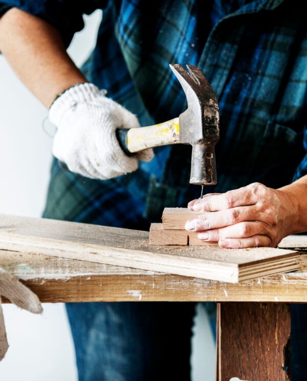 Woman carpenter using hammer pushing nail on a wood